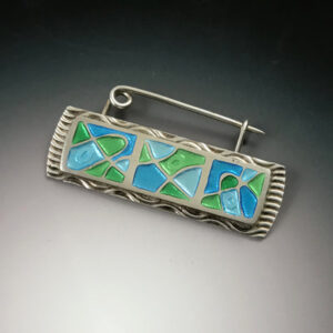 Blue and green enamel design on a silver pin
